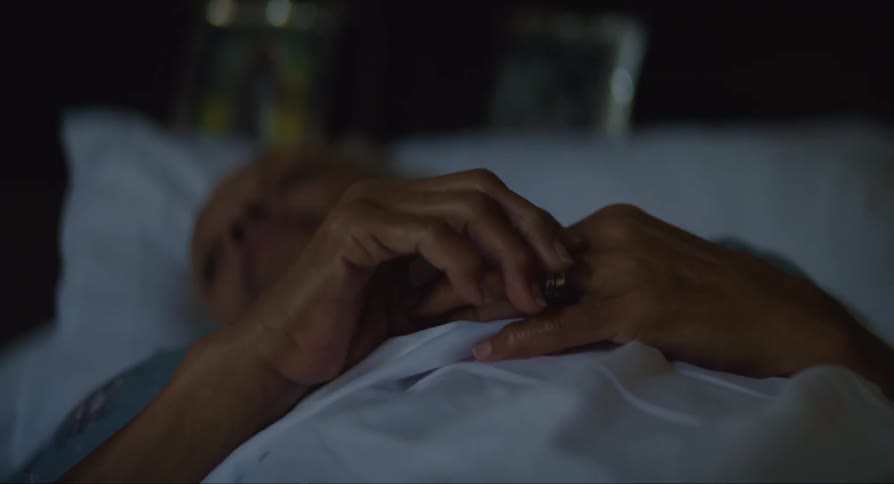 An old woman lying down using her hands to fiddle with her ring on her finger