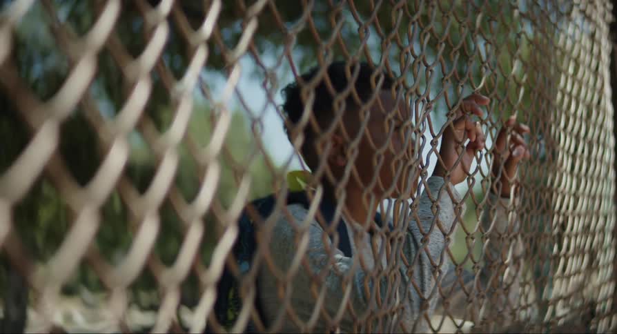 Child placing their hands on the fence observing and then walking away