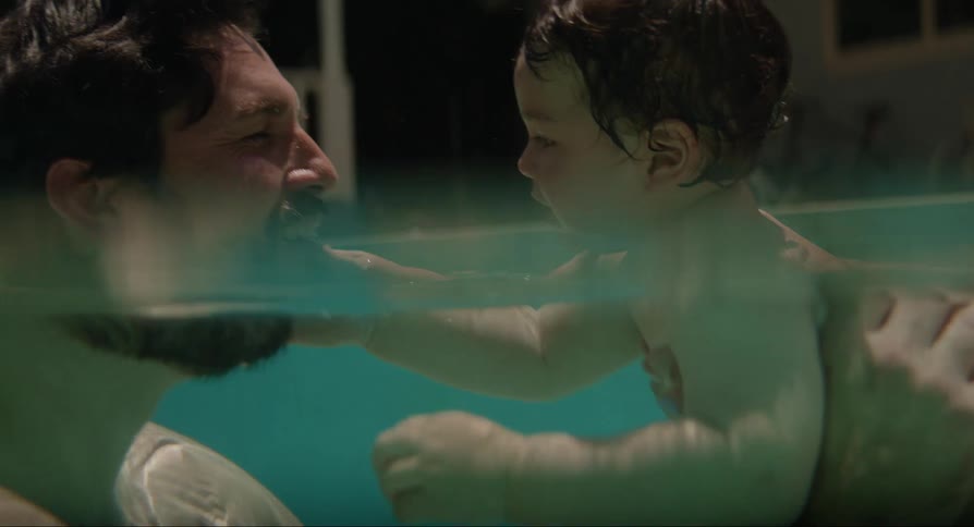 A father playing with his son and kissing him as they play in the water
