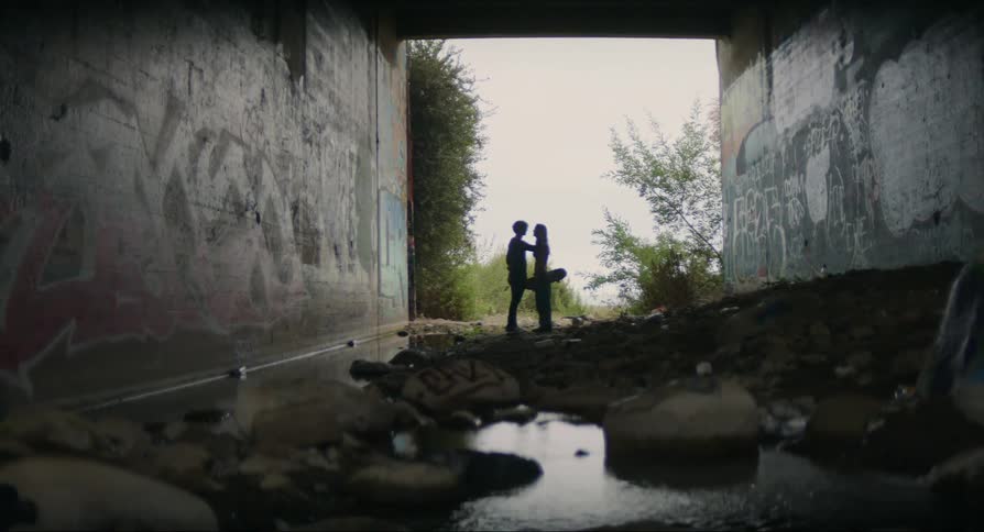 Friends stand and talk at end of drainage culvert