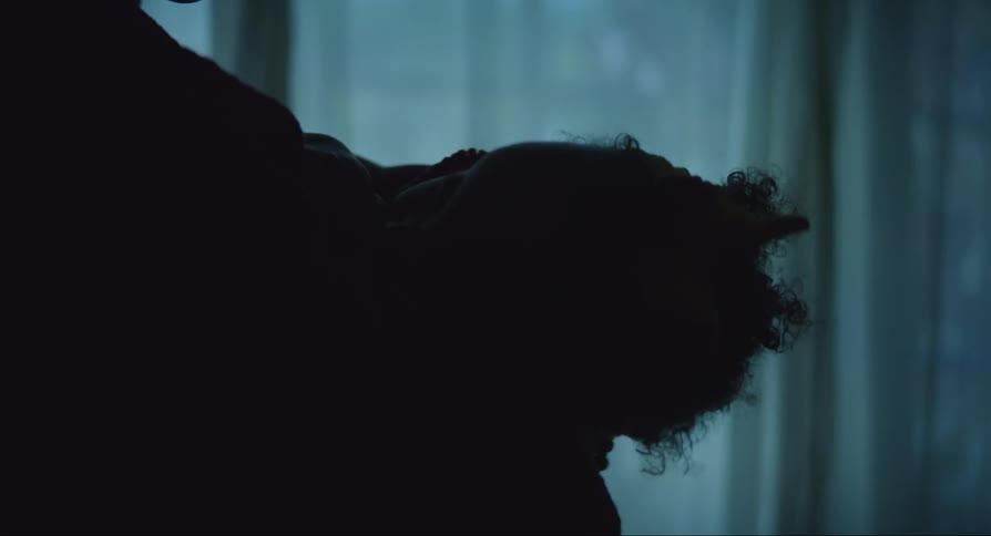 Mother holds child in arms near window in silhouette