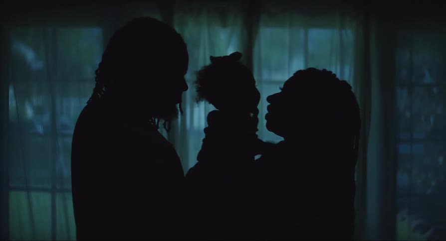 A couple hold their baby in the dark room