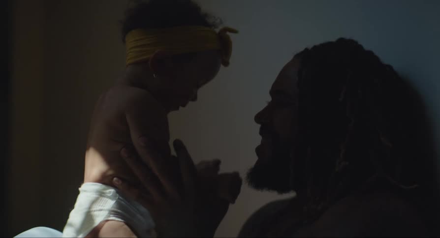 A father kisses his baby daughter while playing with her on his lap