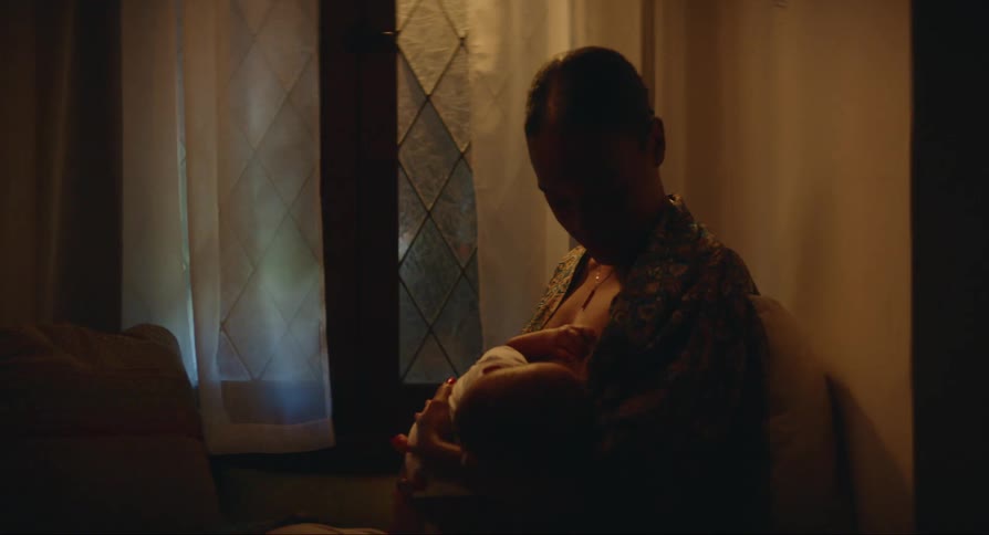Mother sits near window nursing her baby