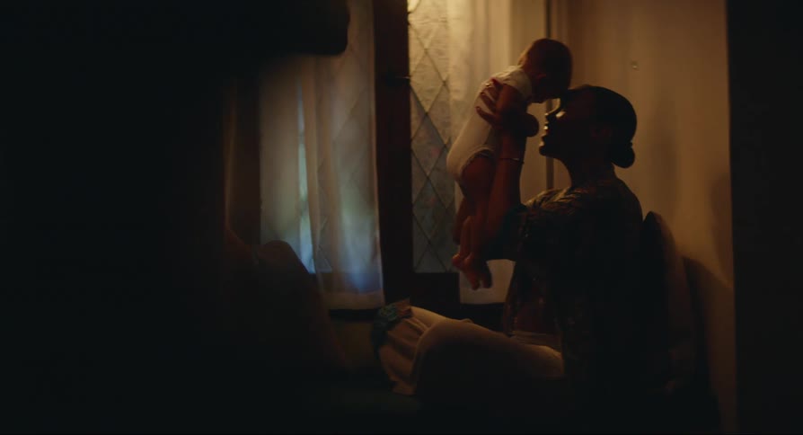 A seated woman is playing with her baby