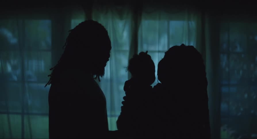 Silhouette of a father and mother holding their baby affectionately