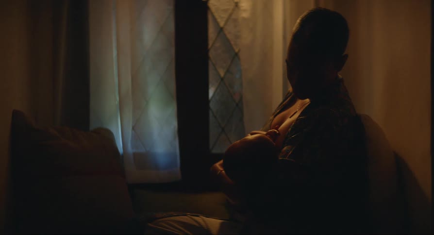 A woman rocks a baby to sleep as she breastfeeds it
