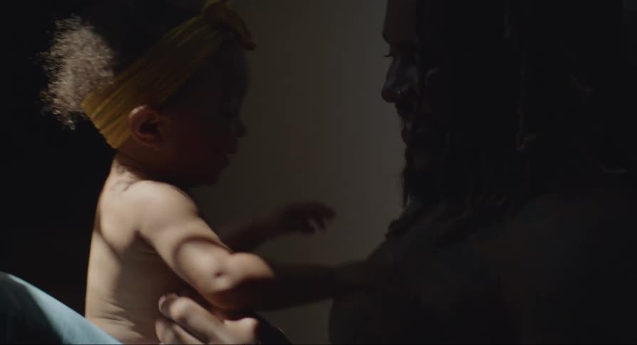 Father with beard and tattoo holds baby with diaper playing