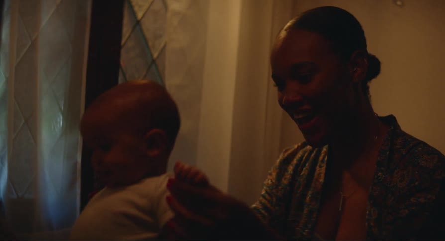 Mother smiling and playing with the baby in bed