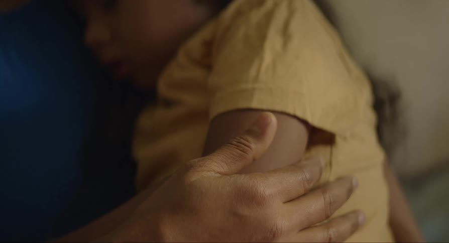 A person stroking a childs arm as he sleeps