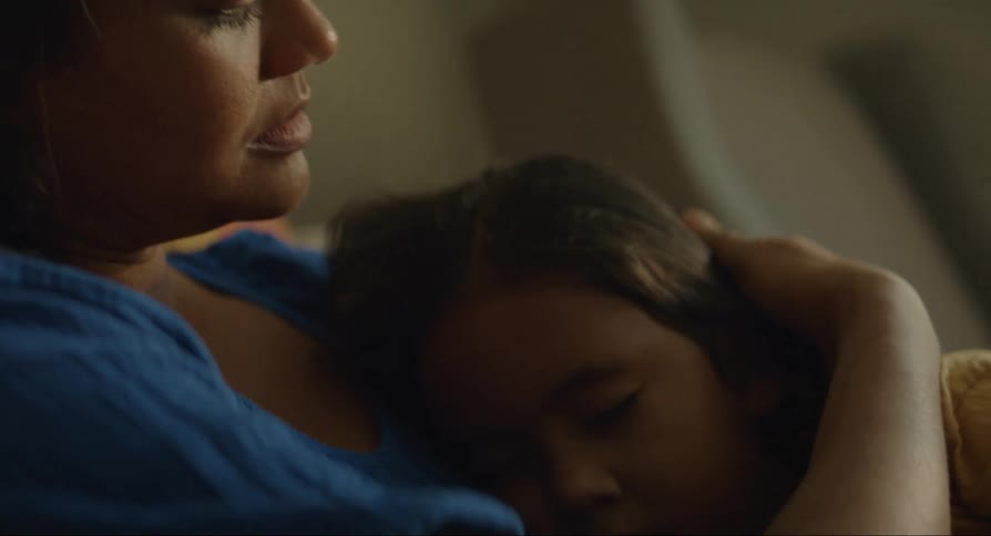 A woman stroking the hair of her daughter sleeping in her lap