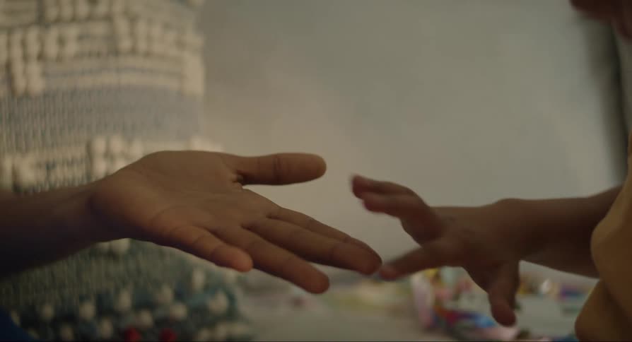 Close up of a childs hands on an adults hands in front of them as they are both seated on the floor