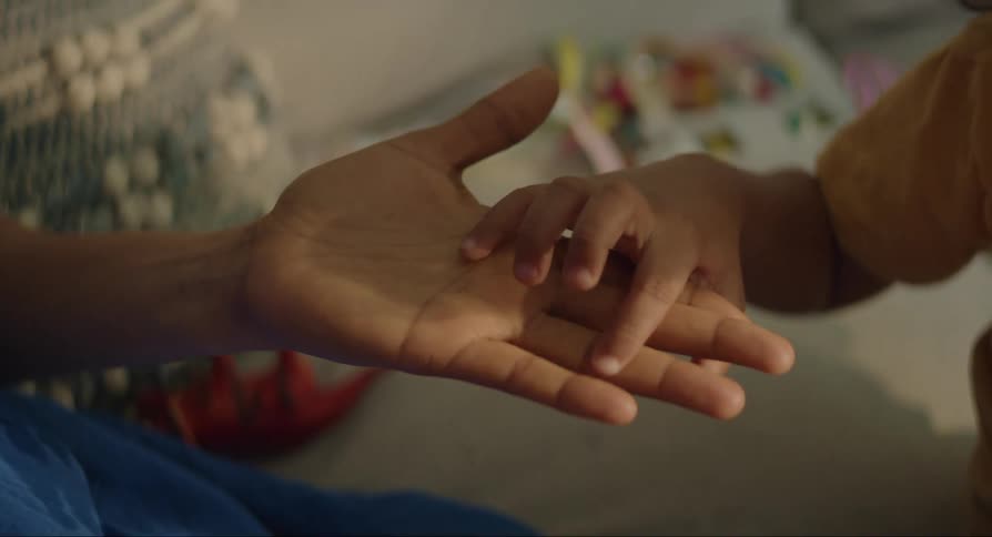 Child in yellow t shirt touches mothers fingers