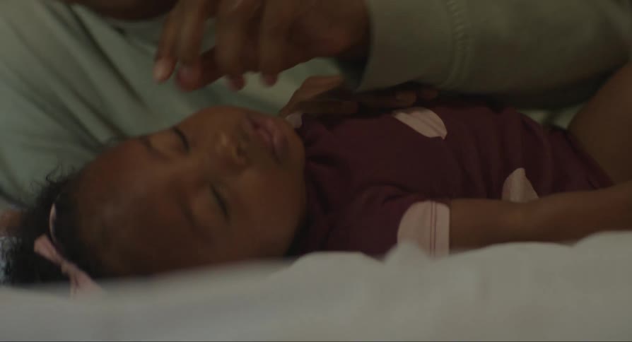Mother lies on bed with baby daughter