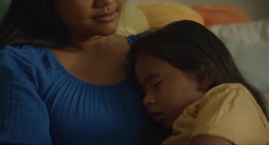 Mother sitting on the sofa and her daughter sleeping on her chest