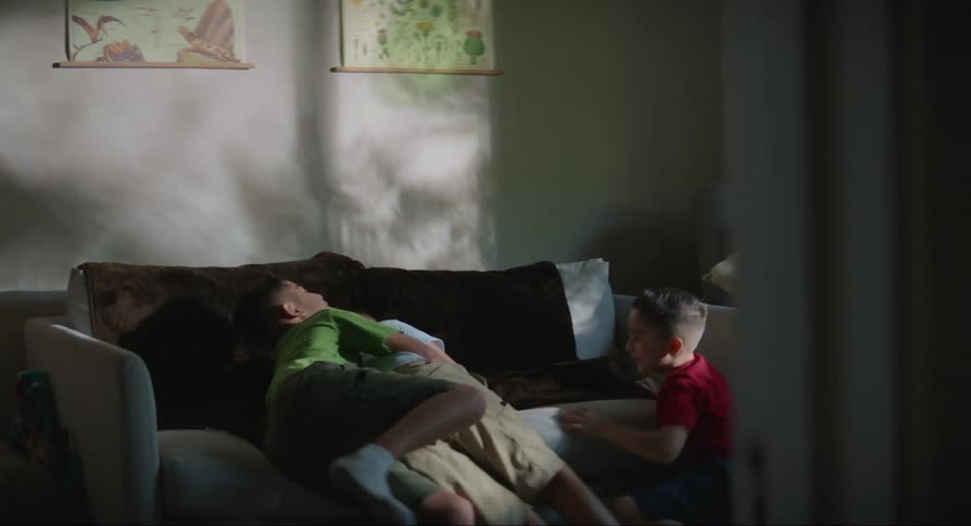 Three boys play and fall onto couch