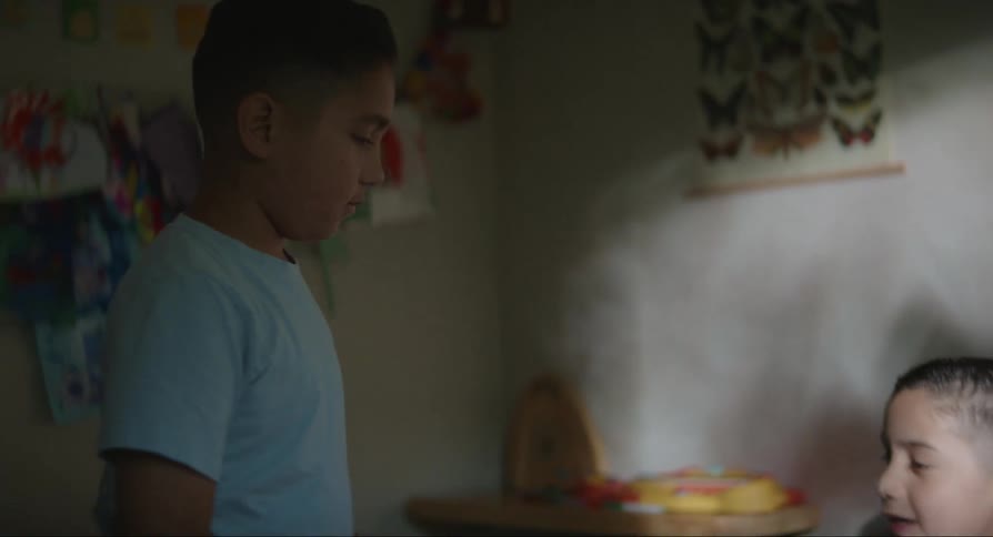 Two boys in a room fighting over a toy while another boy watches