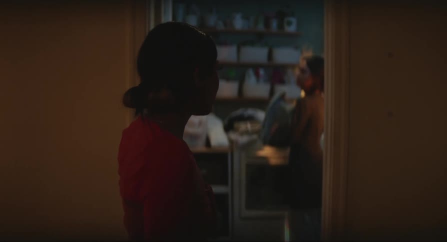 Two women stand near doorframe indoors arguing