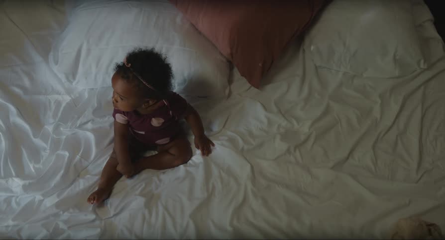 Baby girl on top of bed watching