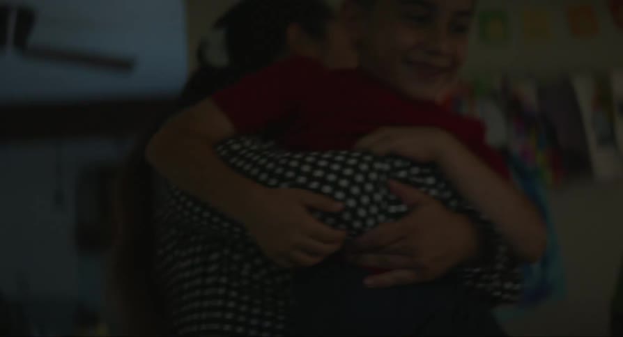 A woman picks up a boy from a couch and takes him to another room pulling him away from another boy