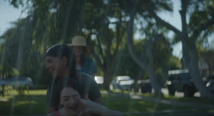 Two children play around in the sprinklers
