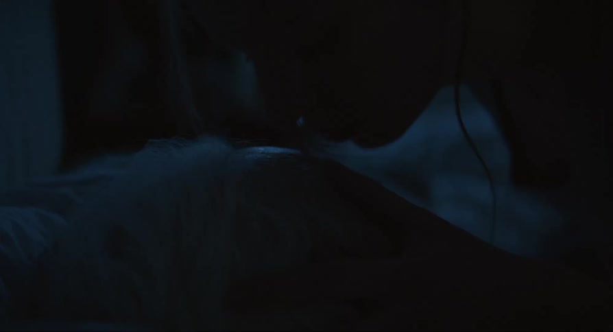 A young woman kisses her grandfathers face while lying on the bed