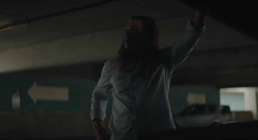 A man watching the hood of a car while talking on the phone and hanging up with a worried look