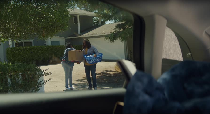 Two women carrying boxes in their hands embrace and say goodbye