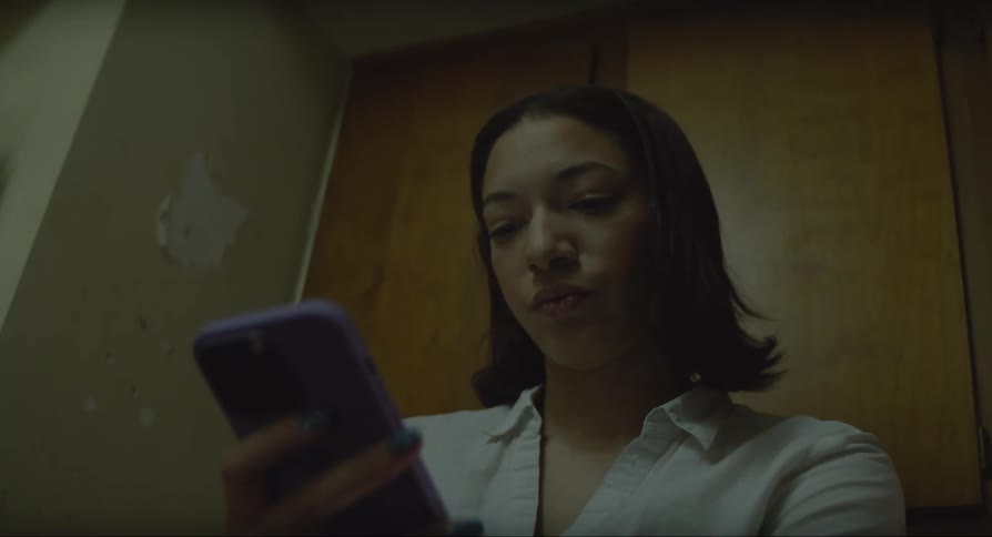 Woman looks at cell phone standing indoors