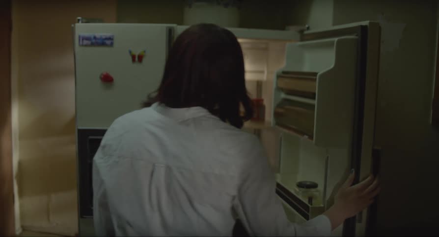 Woman opening the refrigerator taking out a carton of milk smelling it not liking the smell and putting it back in the fridge before closing the door
