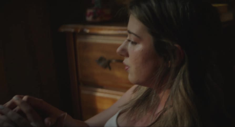 A young woman sitting on the floor while crying and wiping away her tears with her fingers