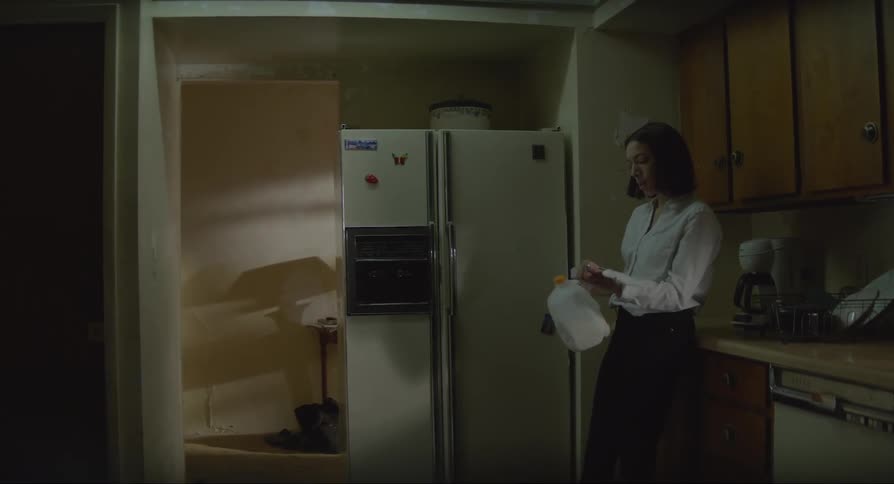 A young woman is drinking milk in the kitchen