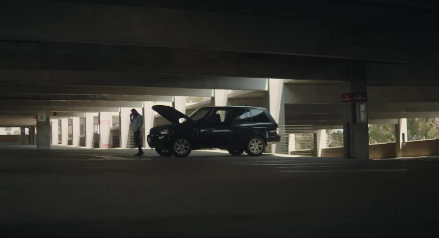 A man stopped in a parking lot with his car broken down