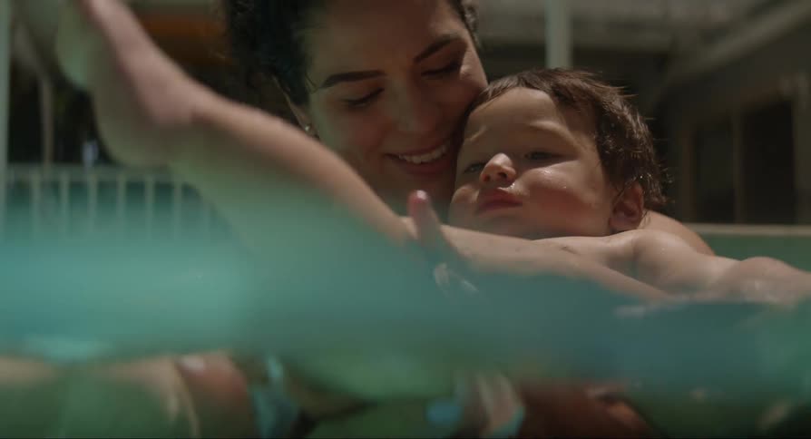 Woman holds baby while splashing and playing in pool