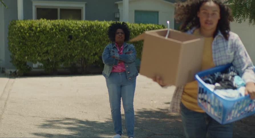 Young man and woman hugging she hands him a box of clothes and he puts it in a vehicle