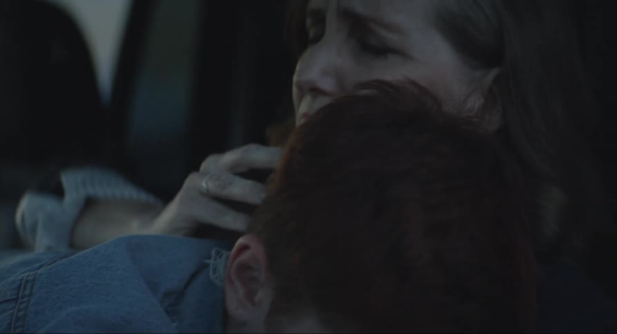 A sad young boy on the lap of a woman who appears to be his grandmother and is consoling him