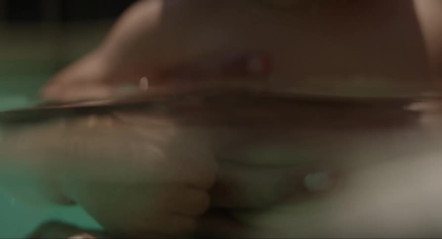 Father and mother hold baby son in water playing