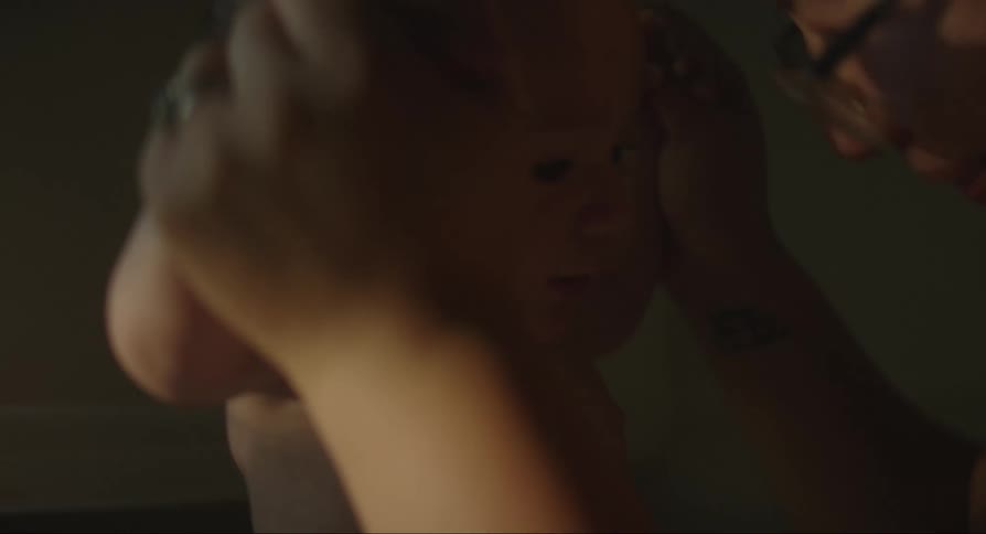 Mother with glasses holds babys hands talking and laughing
