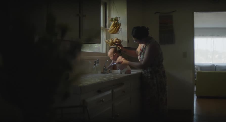 Mother bathing her baby in the kitchen sink
