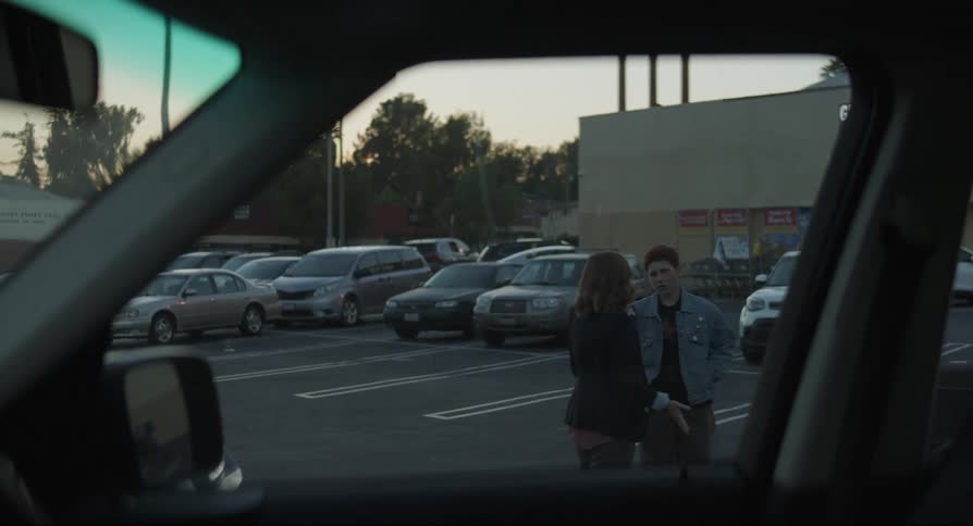 Teenager boy and an adult woman walking on a parking lot having an argument and then stopping and hugging during dusk or dawn
