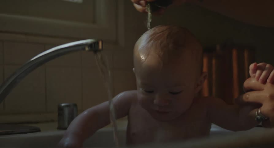 A mother bathing a baby in tap water