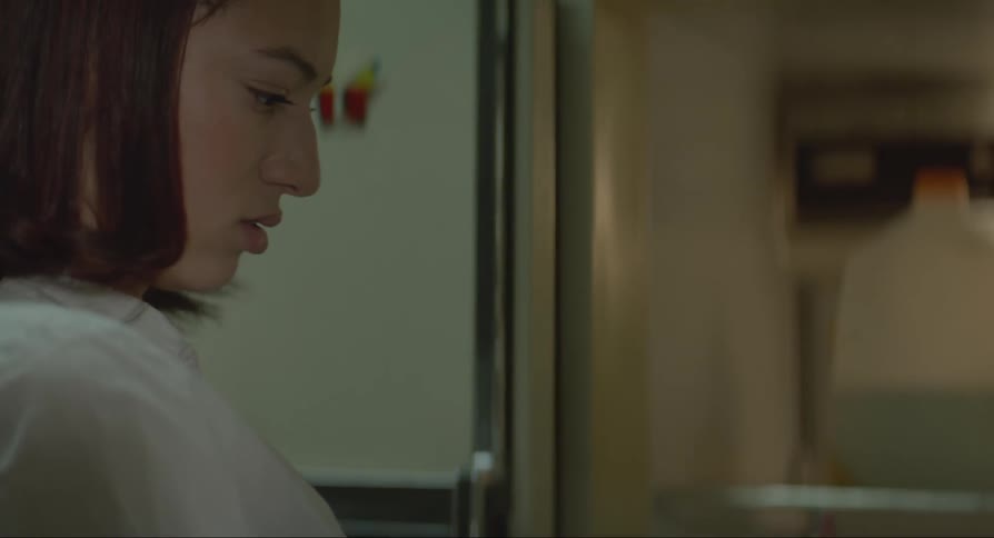A woman is searching through her fridge for food
