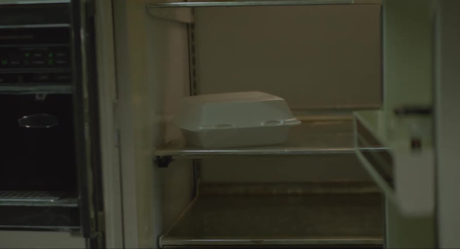 A woman opening a fridge door looking at milk and a food container on the shelf