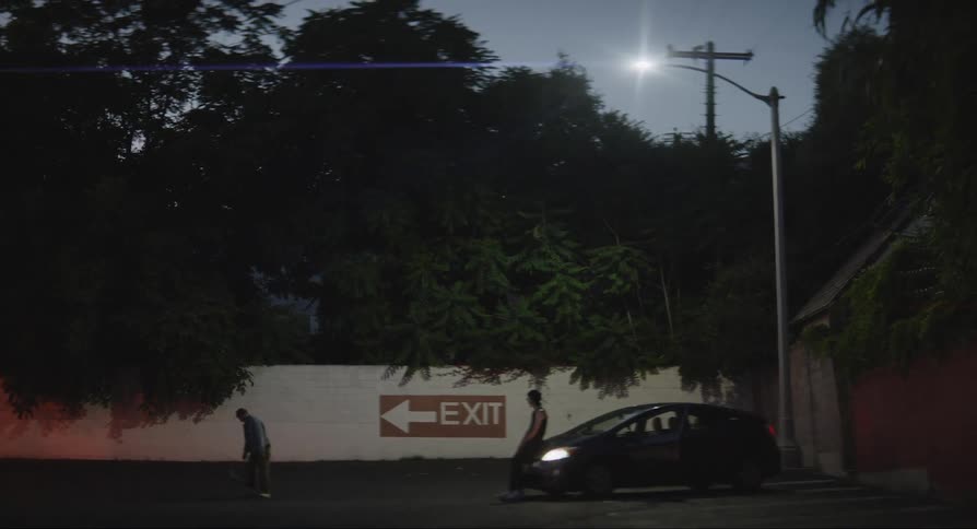 Two guys skateboard in a parking lot at night