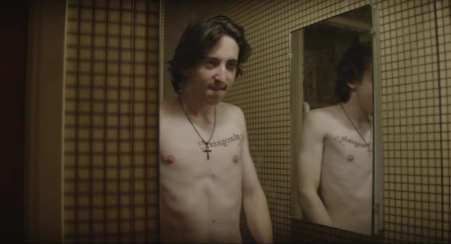 A shirtless young man is standing in the bathroom shadow boxing and rolling his shoulders
