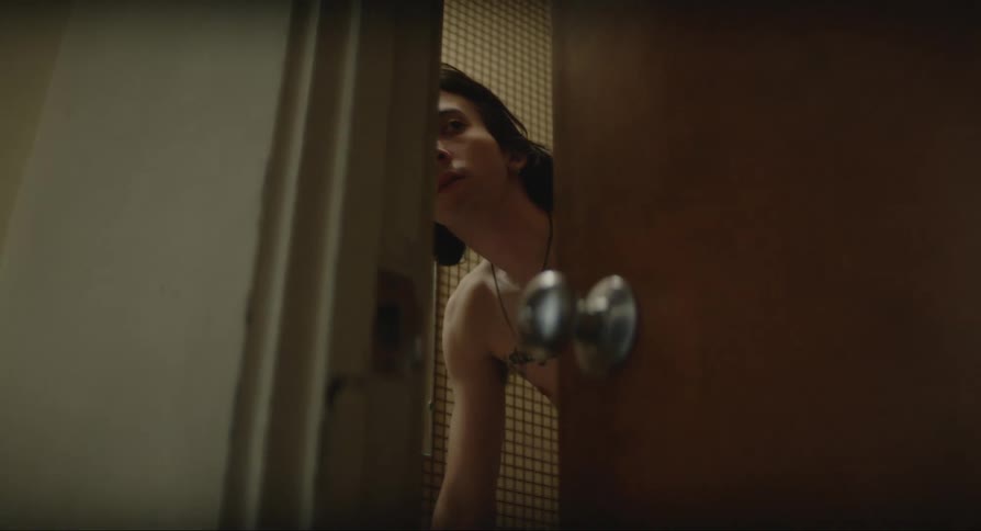 A young man in a room is startled by something and closes the door