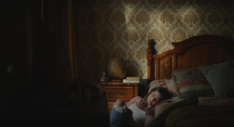 A young girl sitting on the floor beside her bed crying