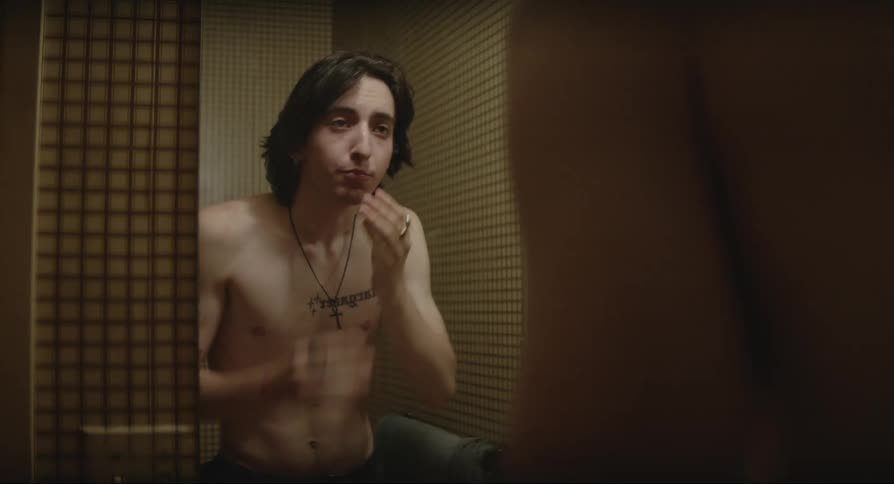 Man facing the mirror washing his face and adjusting his hair