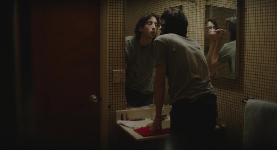 Man standing in front of the mirror applying eyeliner to his eyes