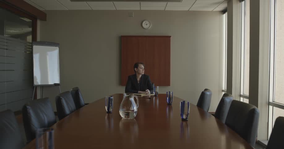 Woman sits at a table in an office writing in a notebook